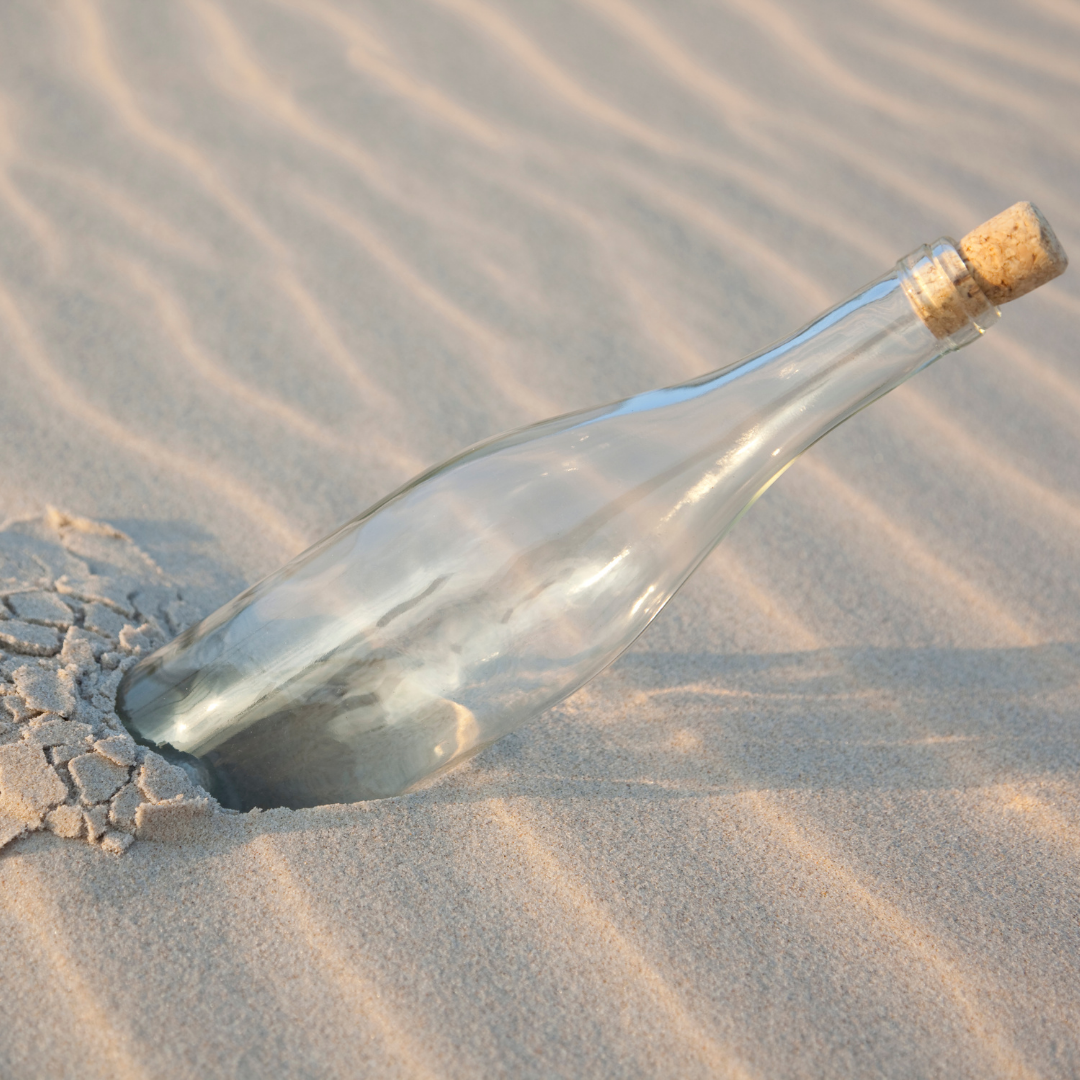 Sustainability, glass bottle in the sand